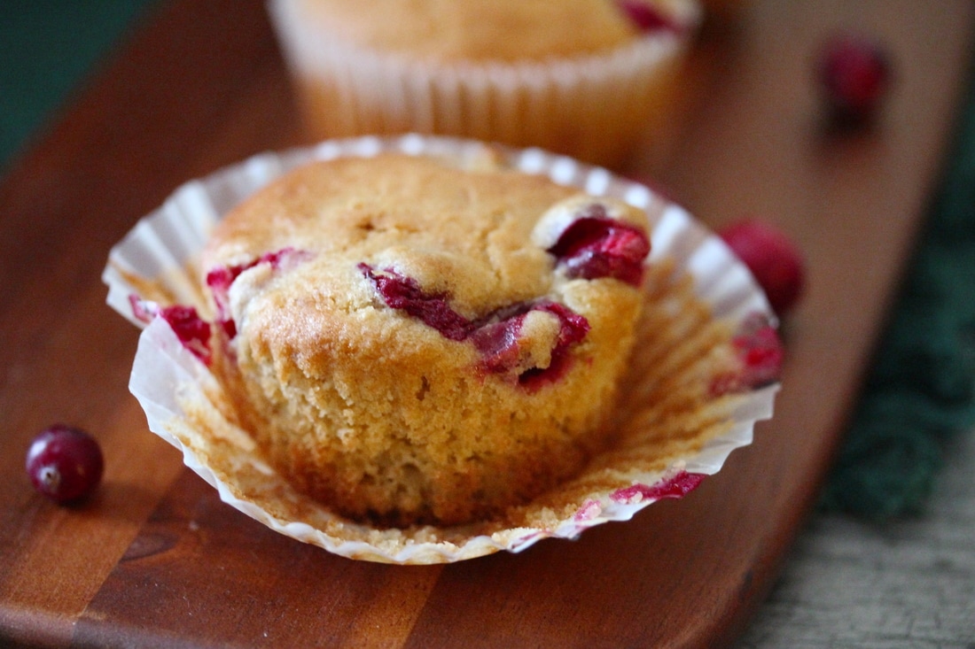 Peeling back the paper liner on a Zesty Cranberry Orange Muffin